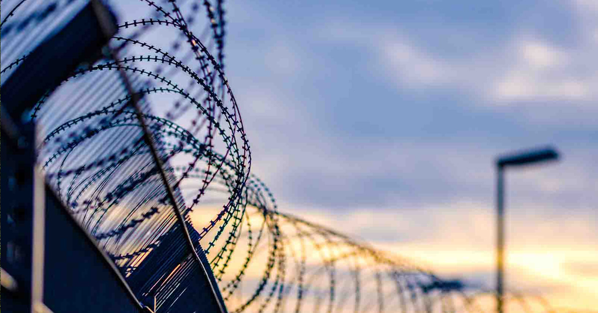 image of jail fence with barbed wire during sunset