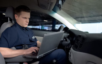 police officer in car with laptop