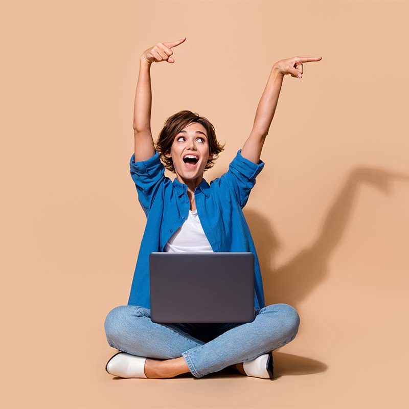 woman pointing with laptop on beige background