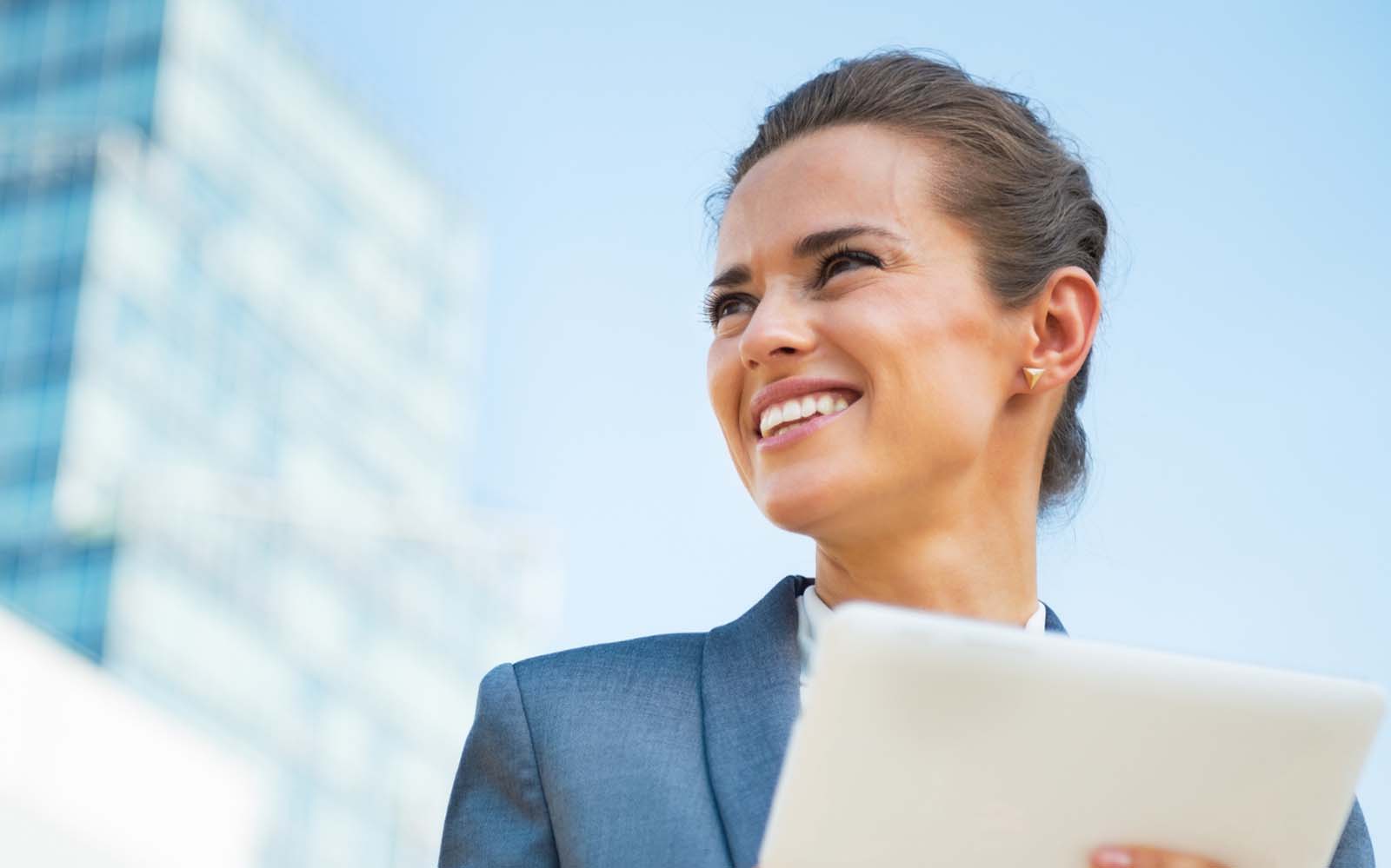 business woman smiling and holding a tablet