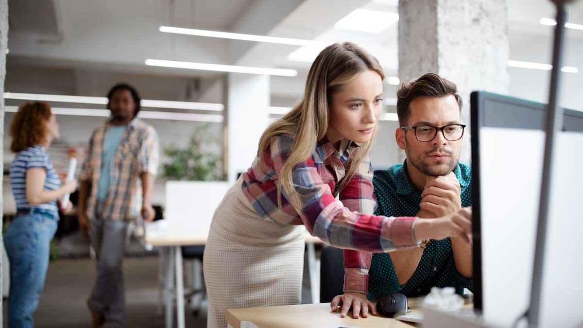 two professional collaborating at a computer desk