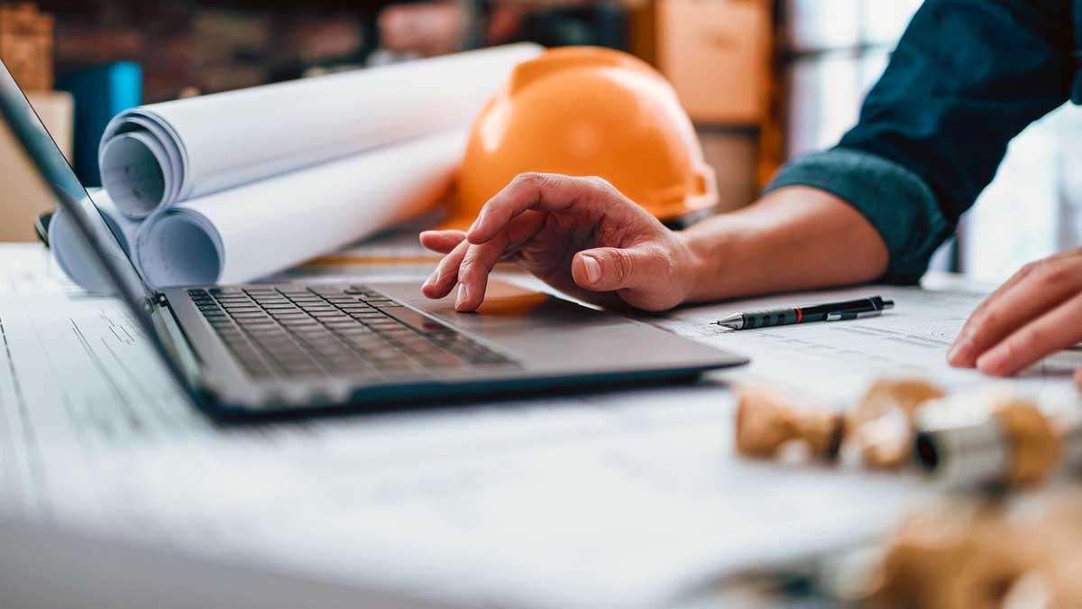 building official reviewing construction plans on laptop in the office