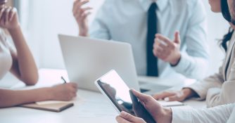 people sitting and discussing at table with laptop and tablet