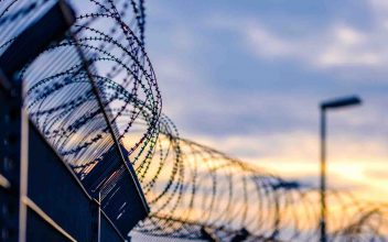 image of jail fence with barbed wire during sunset